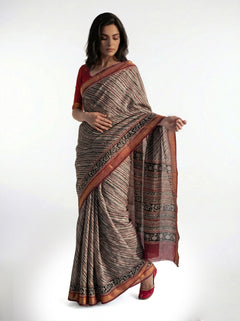 Woman wearing a traditional saree with a patterned border on a white background