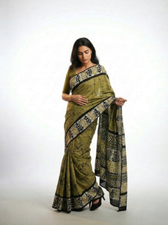 Woman wearing a green saree with black patterns on a white background