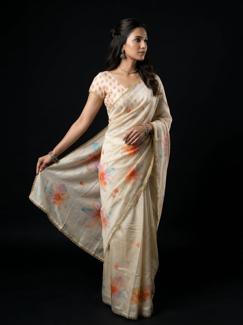 Woman wearing a beige saree with colorful floral patterns on a black background