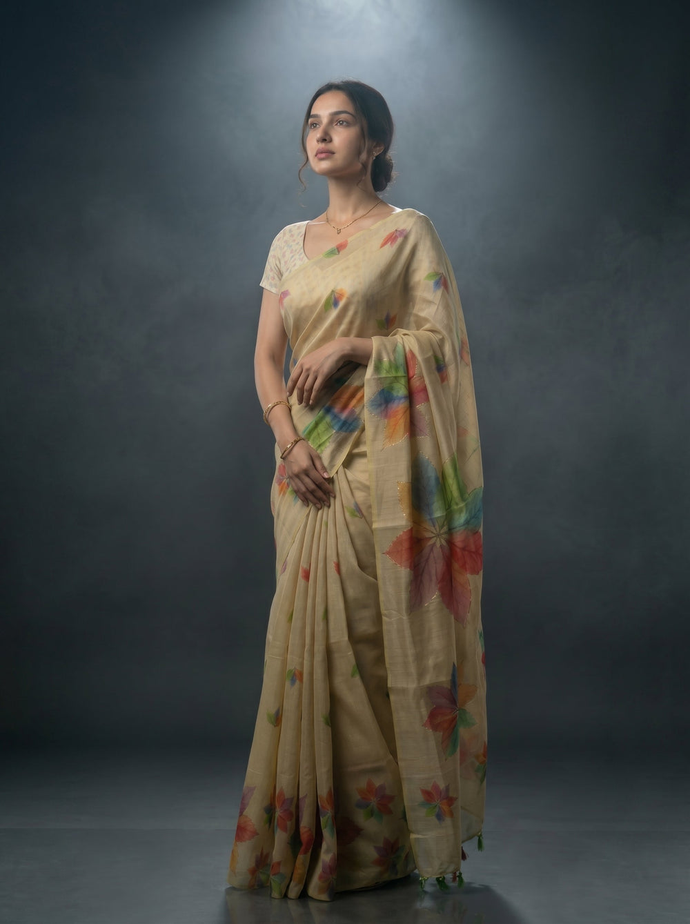 Woman wearing a beige saree with colorful floral patterns against a dark background