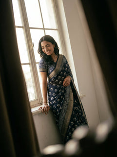 Woman in a blue saree standing by a window