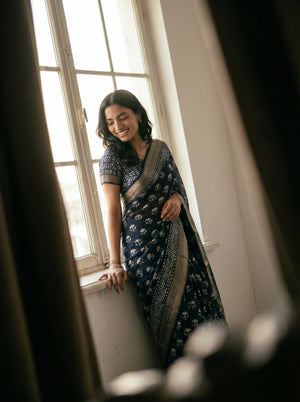 Woman in a blue saree standing by a window