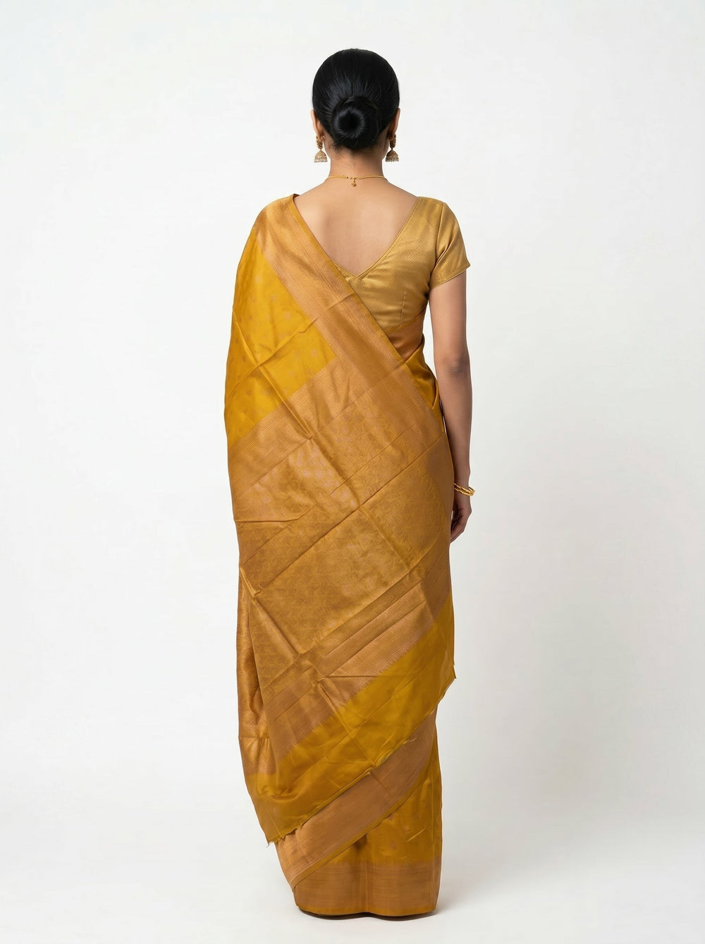 Woman wearing a mustard yellow saree on a gray background