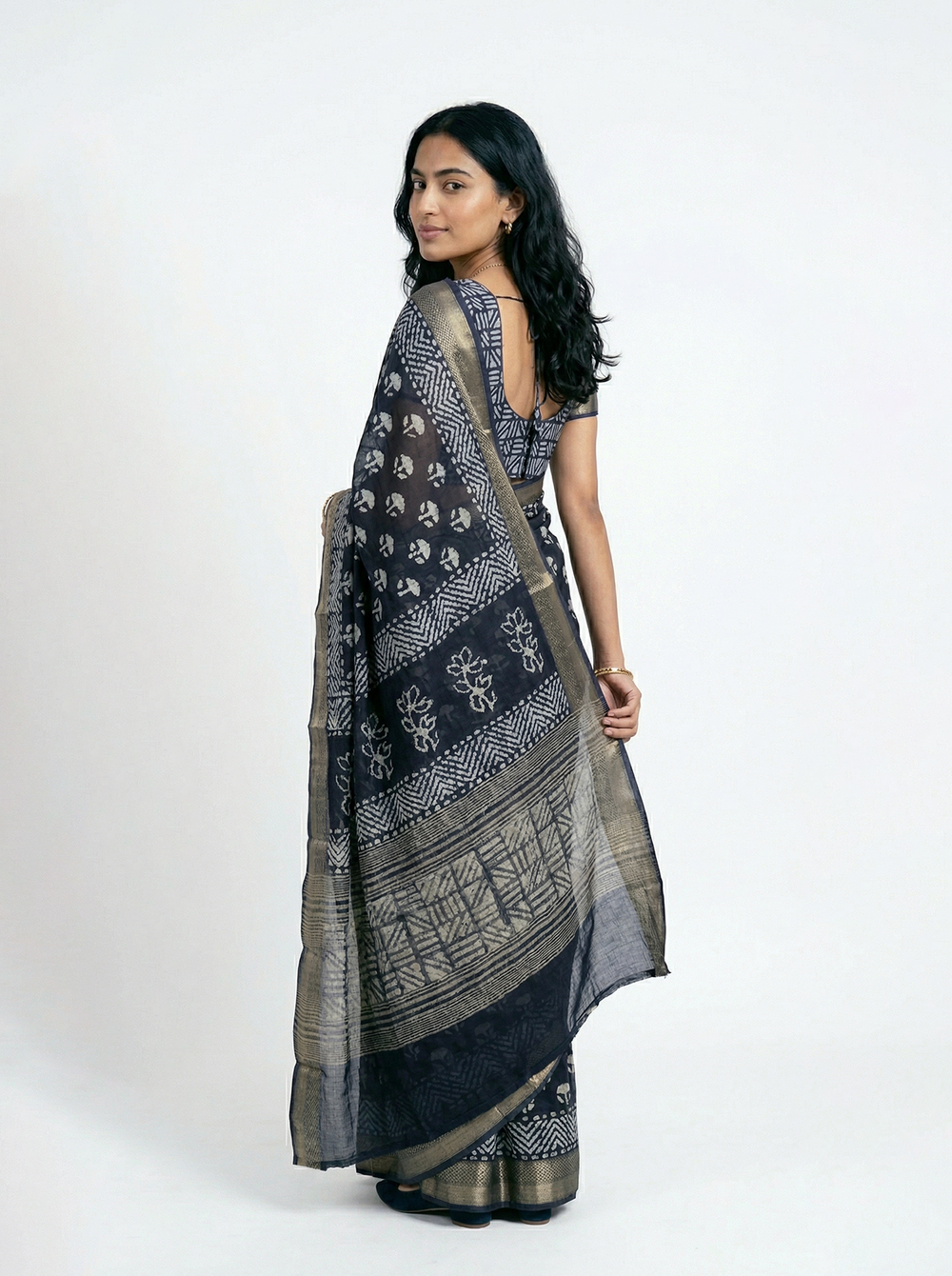 Woman in a blue saree standing by a window