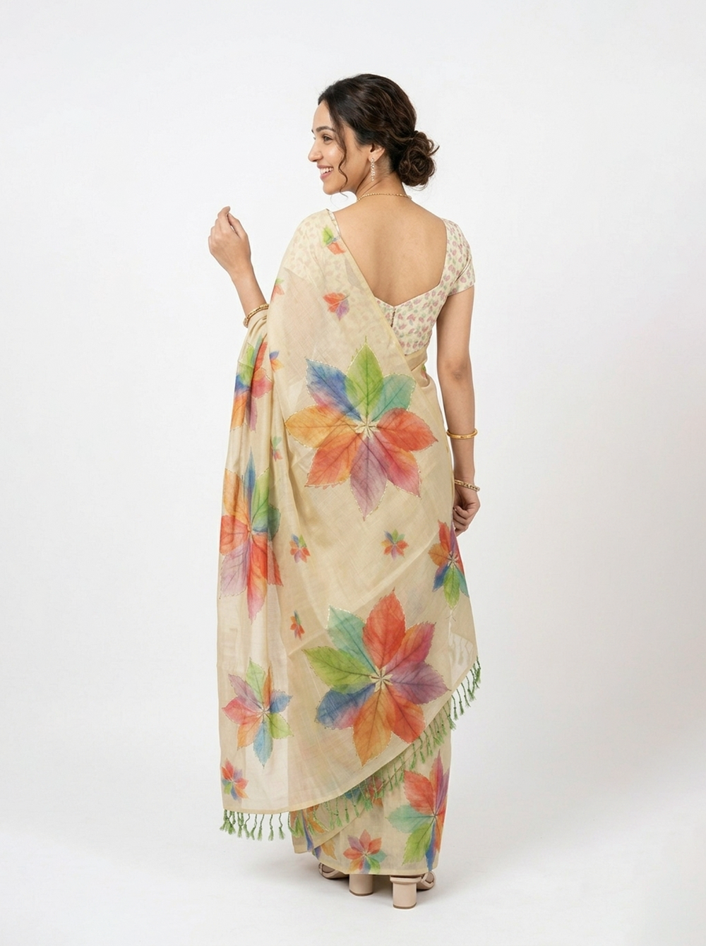 Woman wearing a beige saree with colorful floral patterns against a dark background