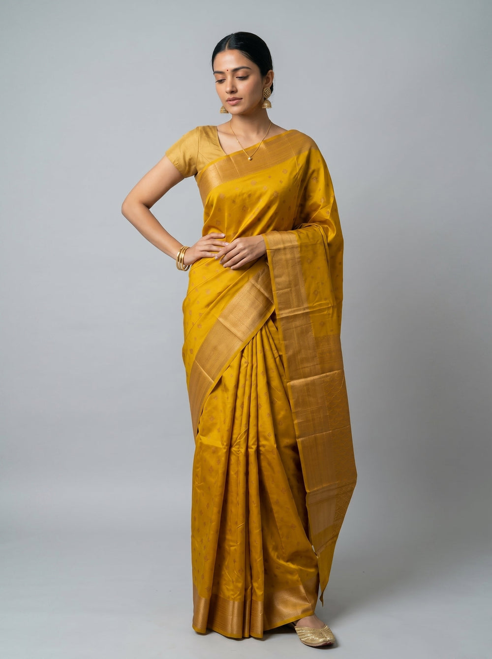 Woman wearing a mustard yellow saree on a gray background