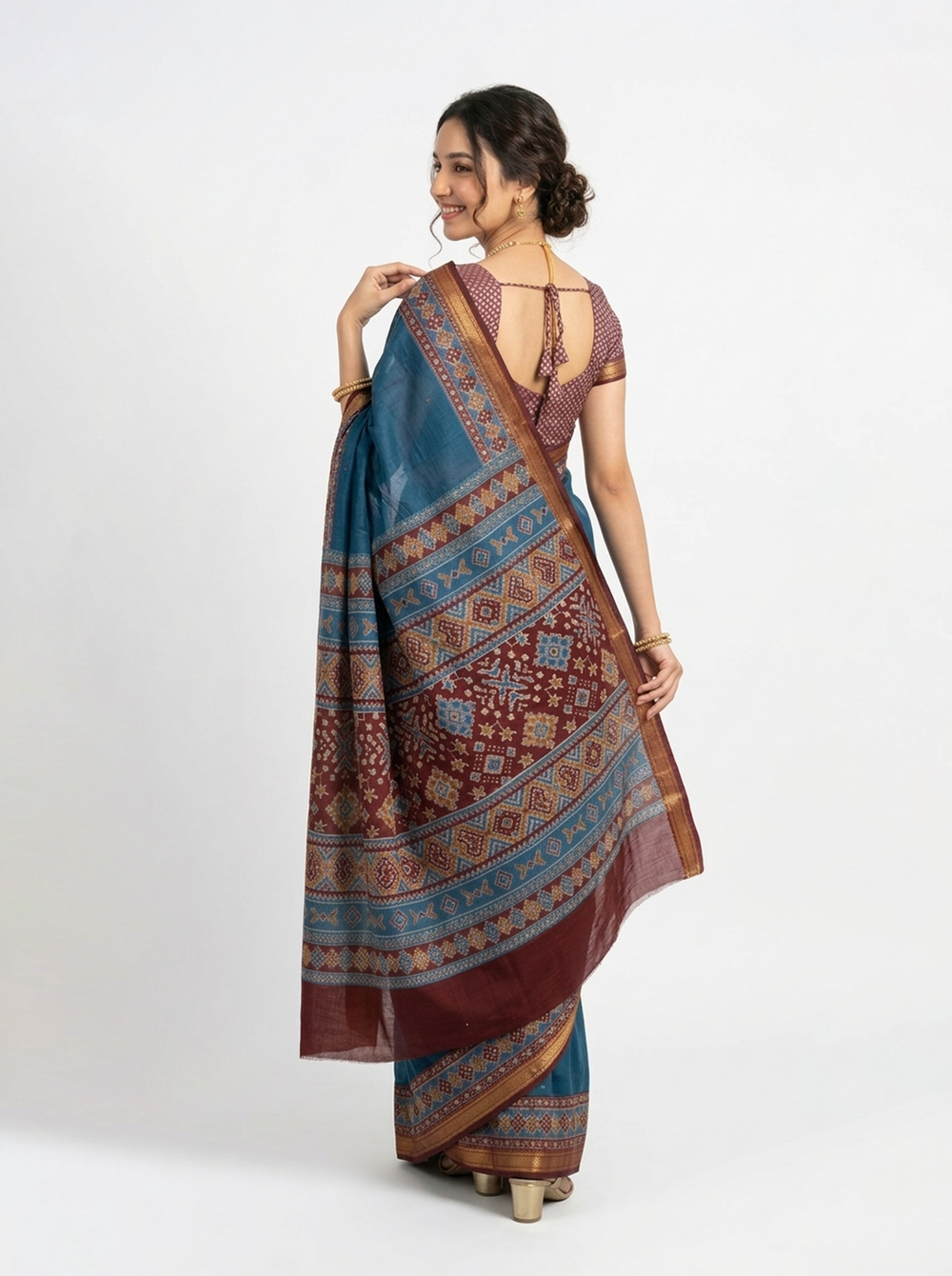 Woman in a blue saree with a brown border standing outdoors.