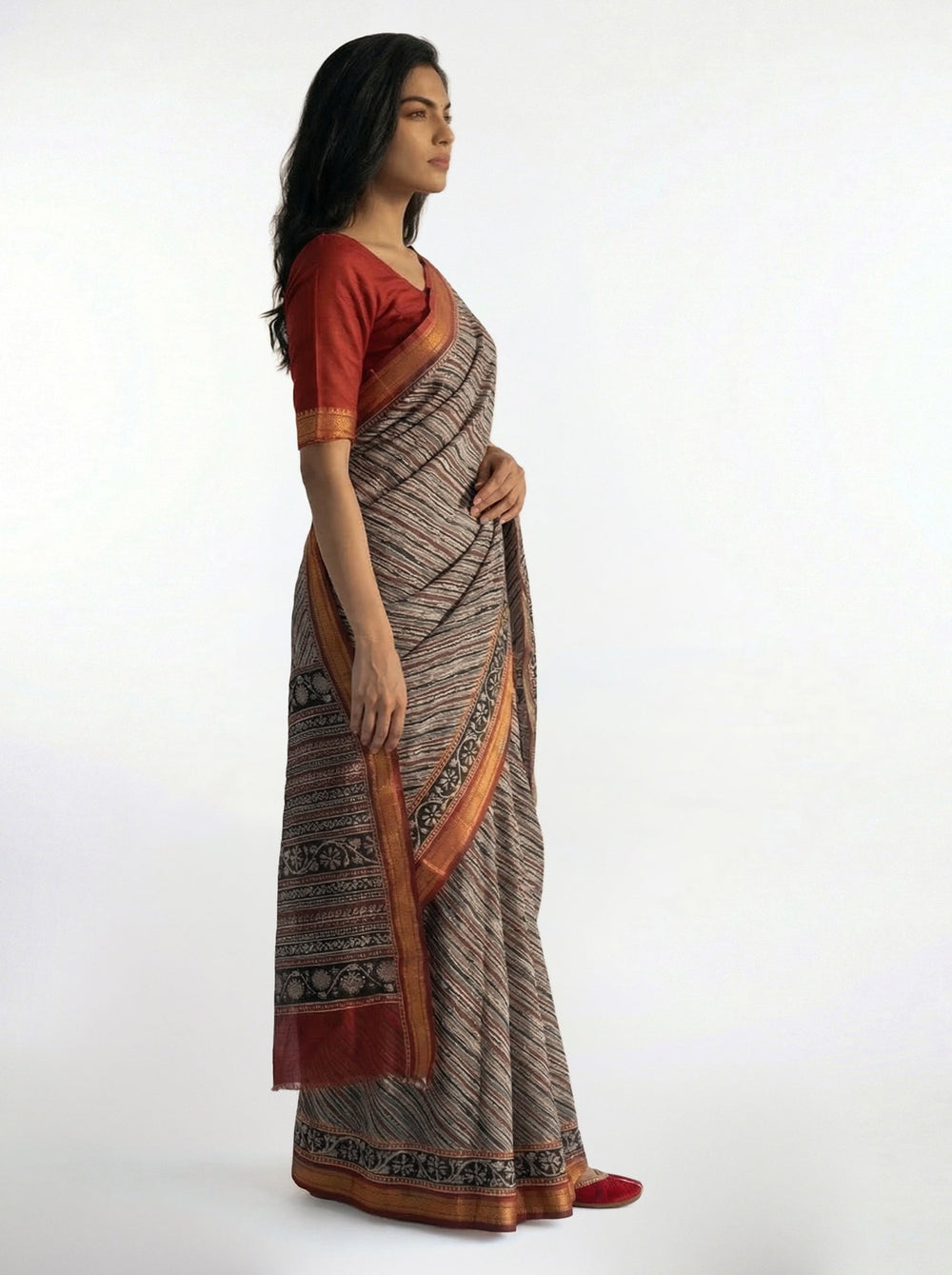 Woman wearing a traditional saree with a patterned border on a white background
