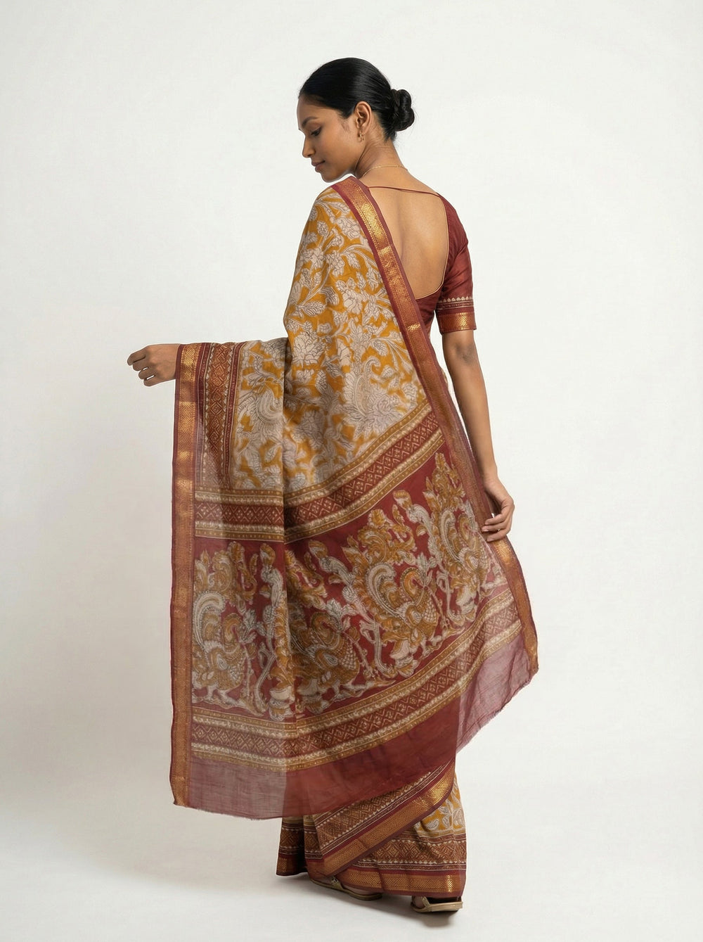 Woman in a patterned saree standing in a bedroom