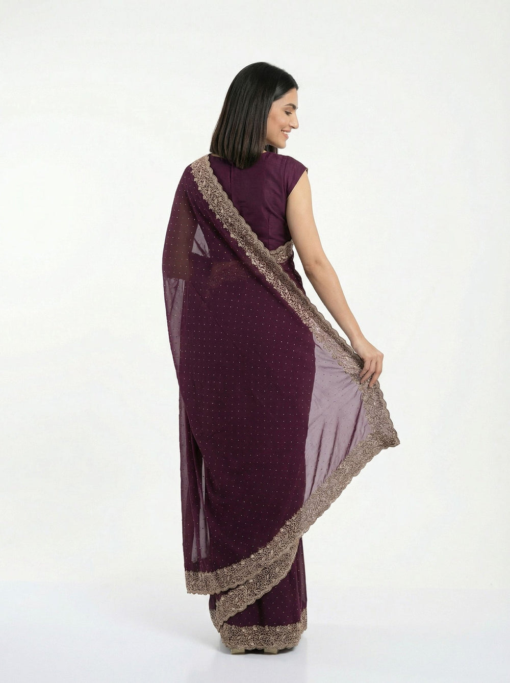 Woman in a purple saree standing on a porch with decorative columns and plants.