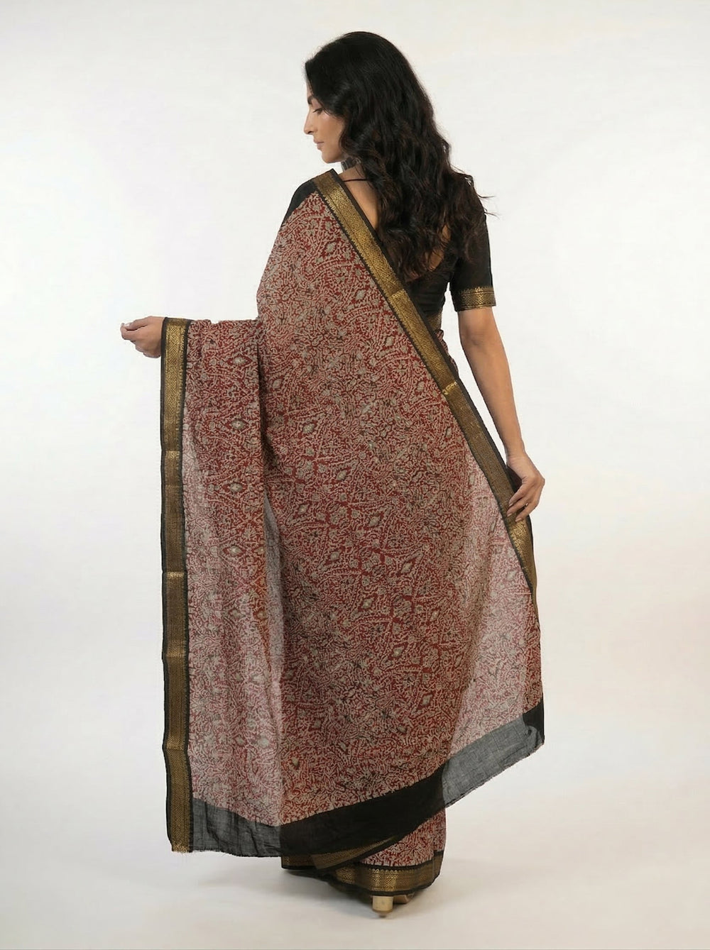 Woman wearing a black saree with a patterned border against an orange background