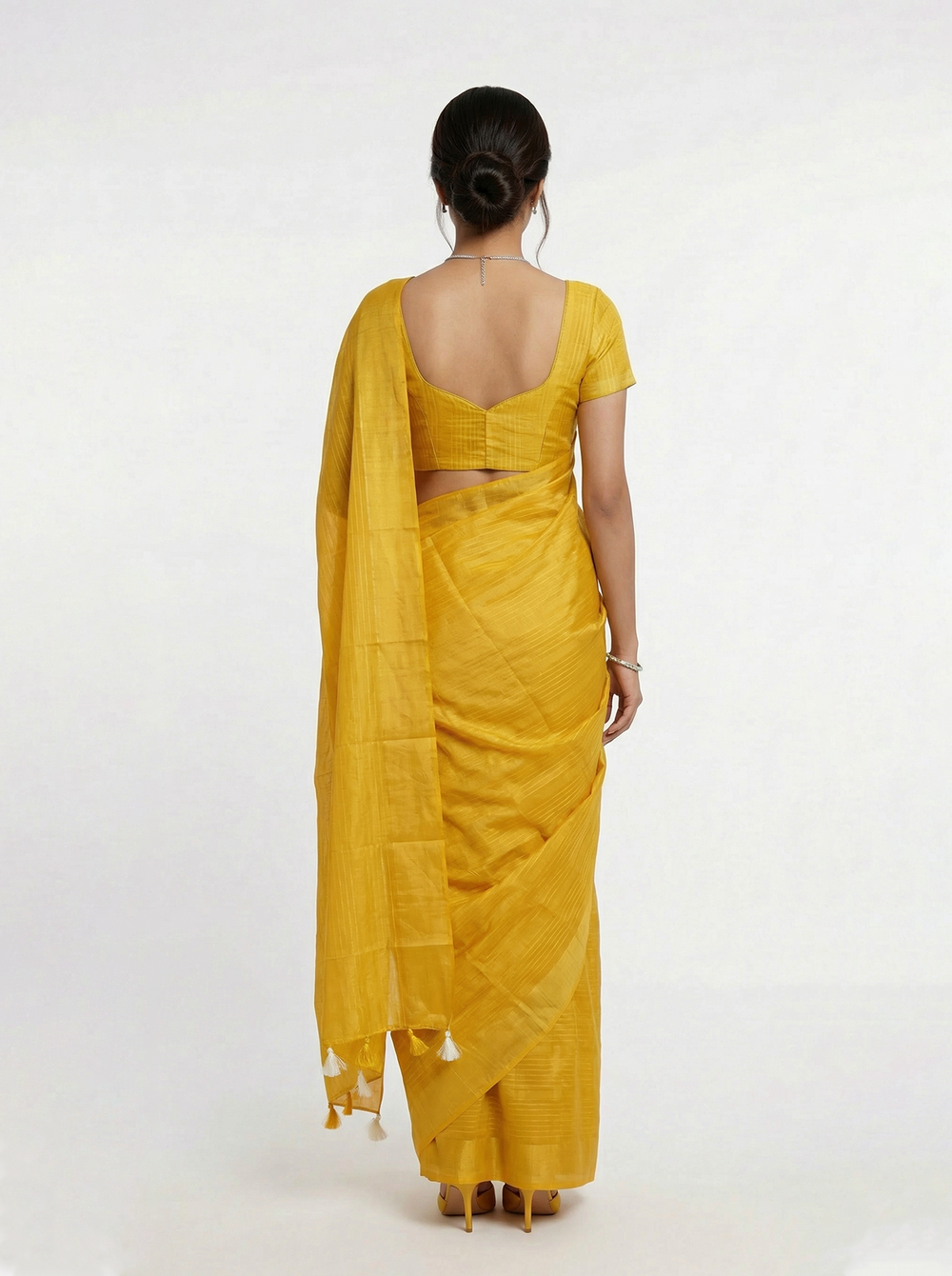Woman wearing a yellow saree against a teal background