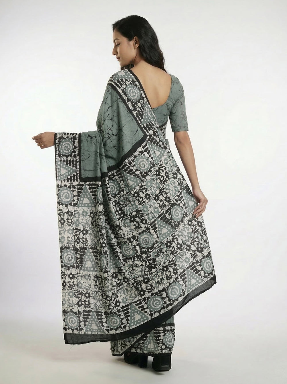 Woman in a traditional saree standing in an architectural setting