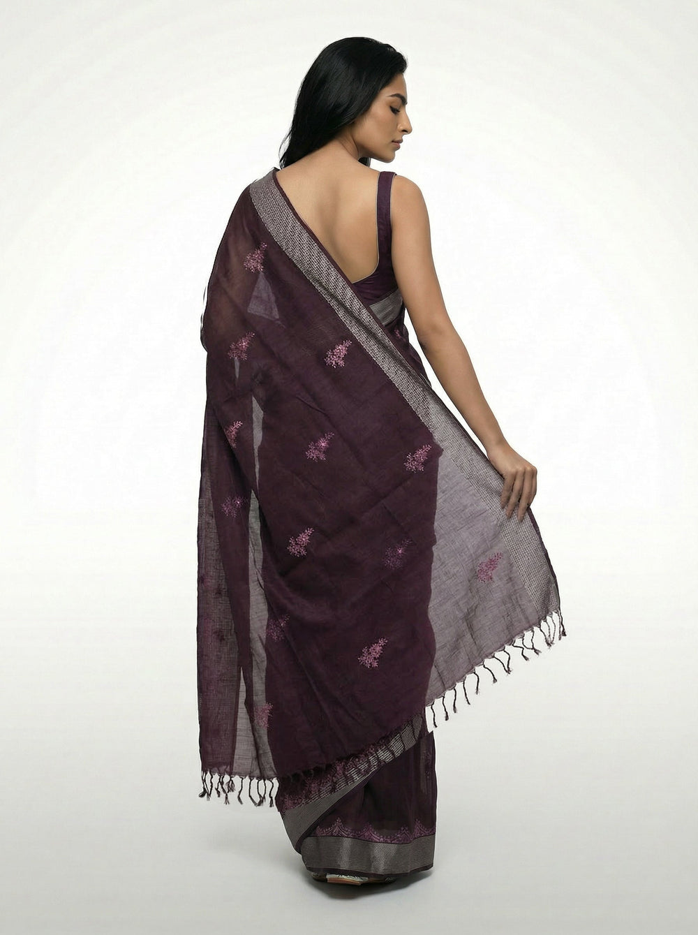 Woman in a purple saree standing in a room with decor elements.