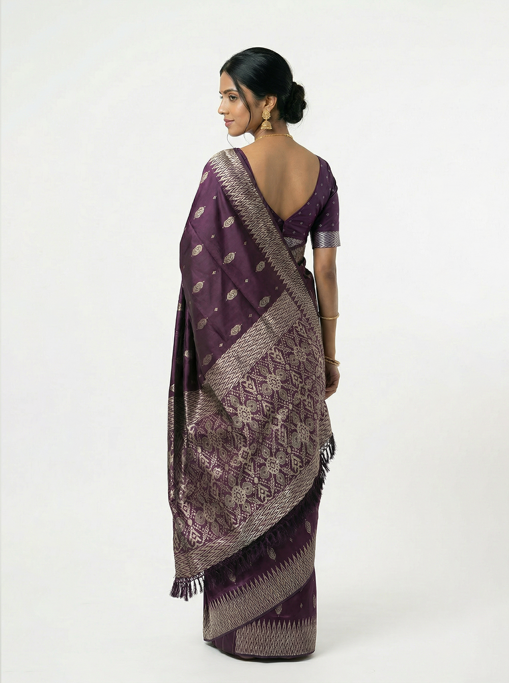 Woman wearing a purple saree with a white pattern on a gray background