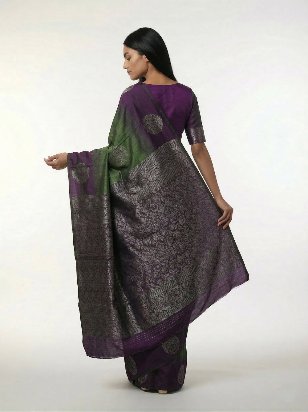 Woman wearing a green and purple saree against a yellow background