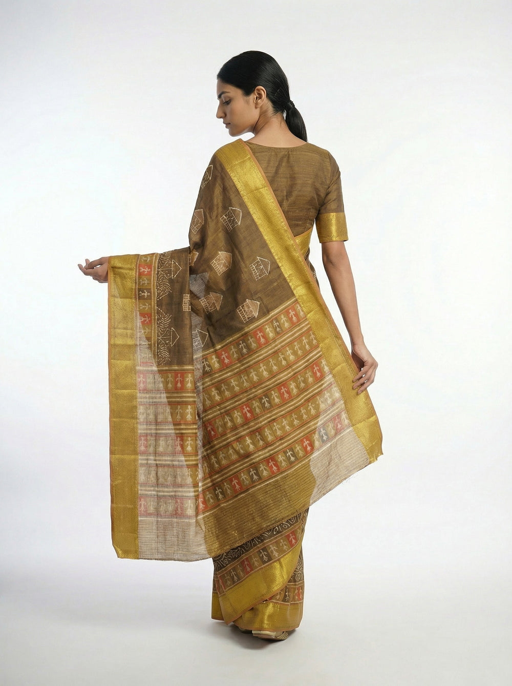 Woman in a traditional saree standing on a wooden floor with plants and architectural elements in the background