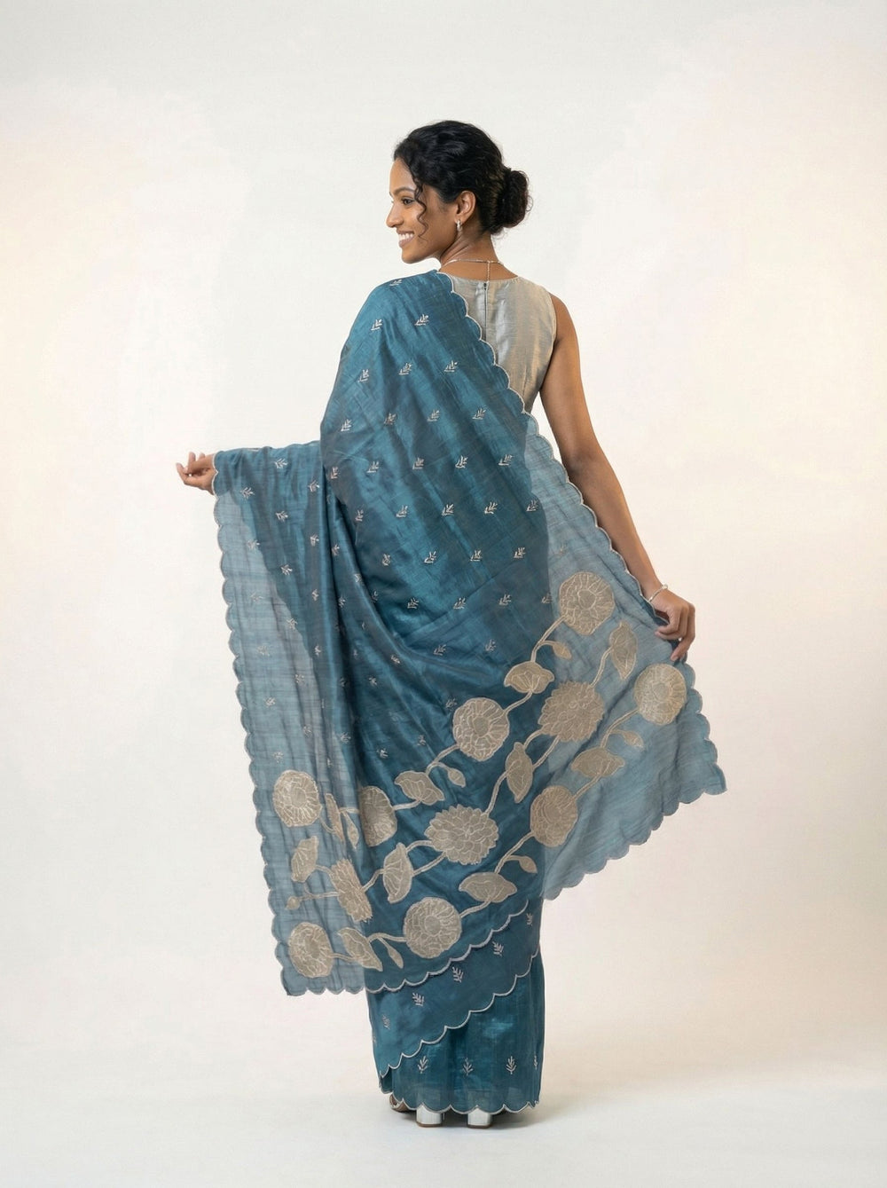 Woman in a blue saree standing in a garden setting