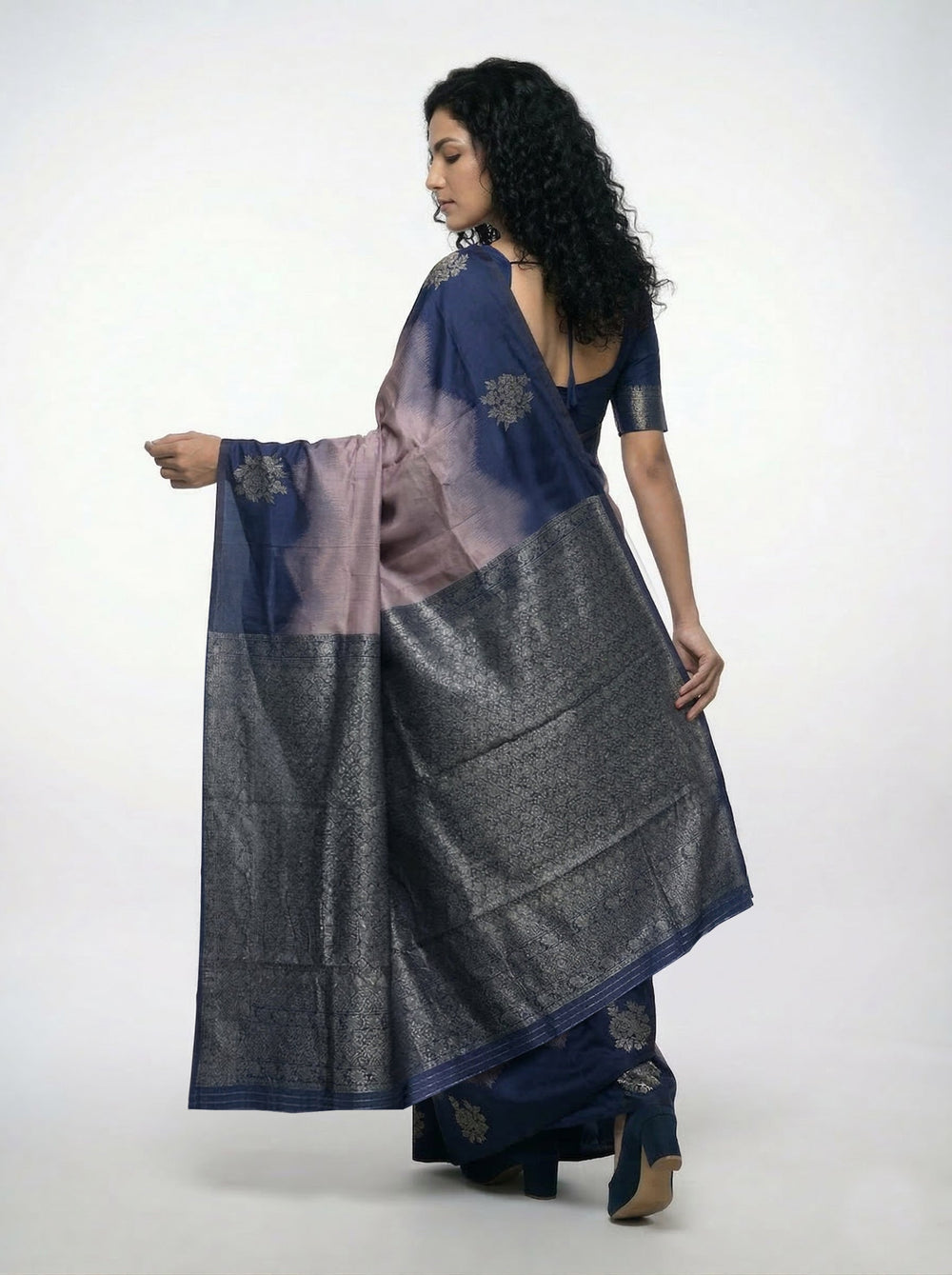 Woman wearing a blue and gray saree against a beige background