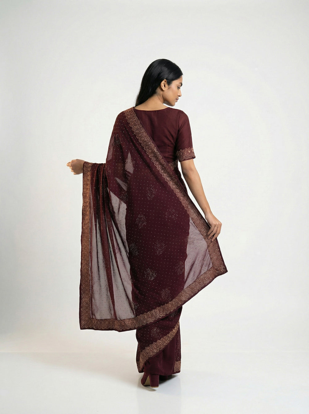 Woman in a maroon saree standing in a garden setting