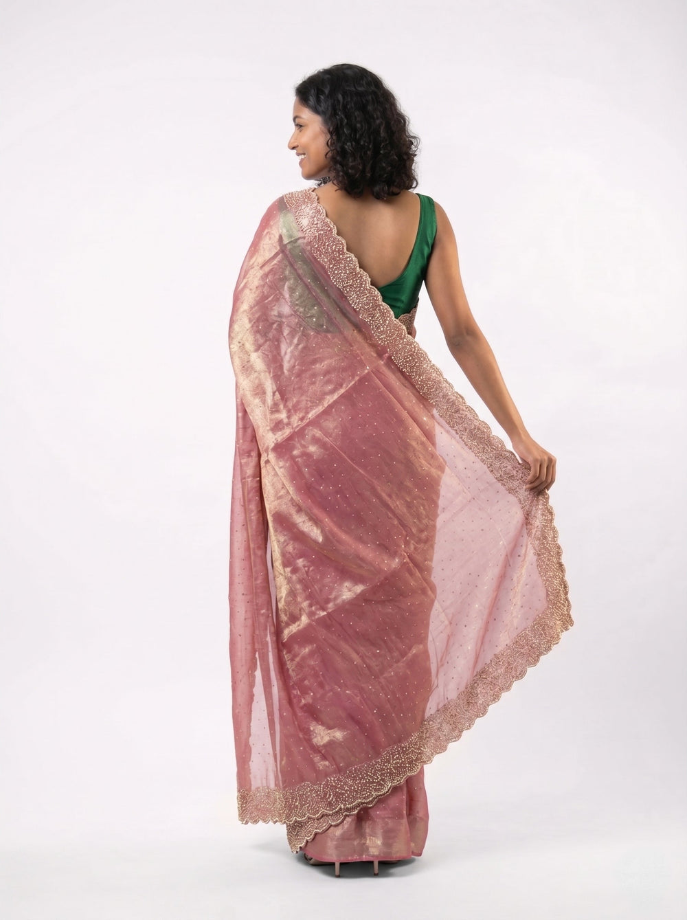 Woman in a pink saree standing in front of an architectural structure