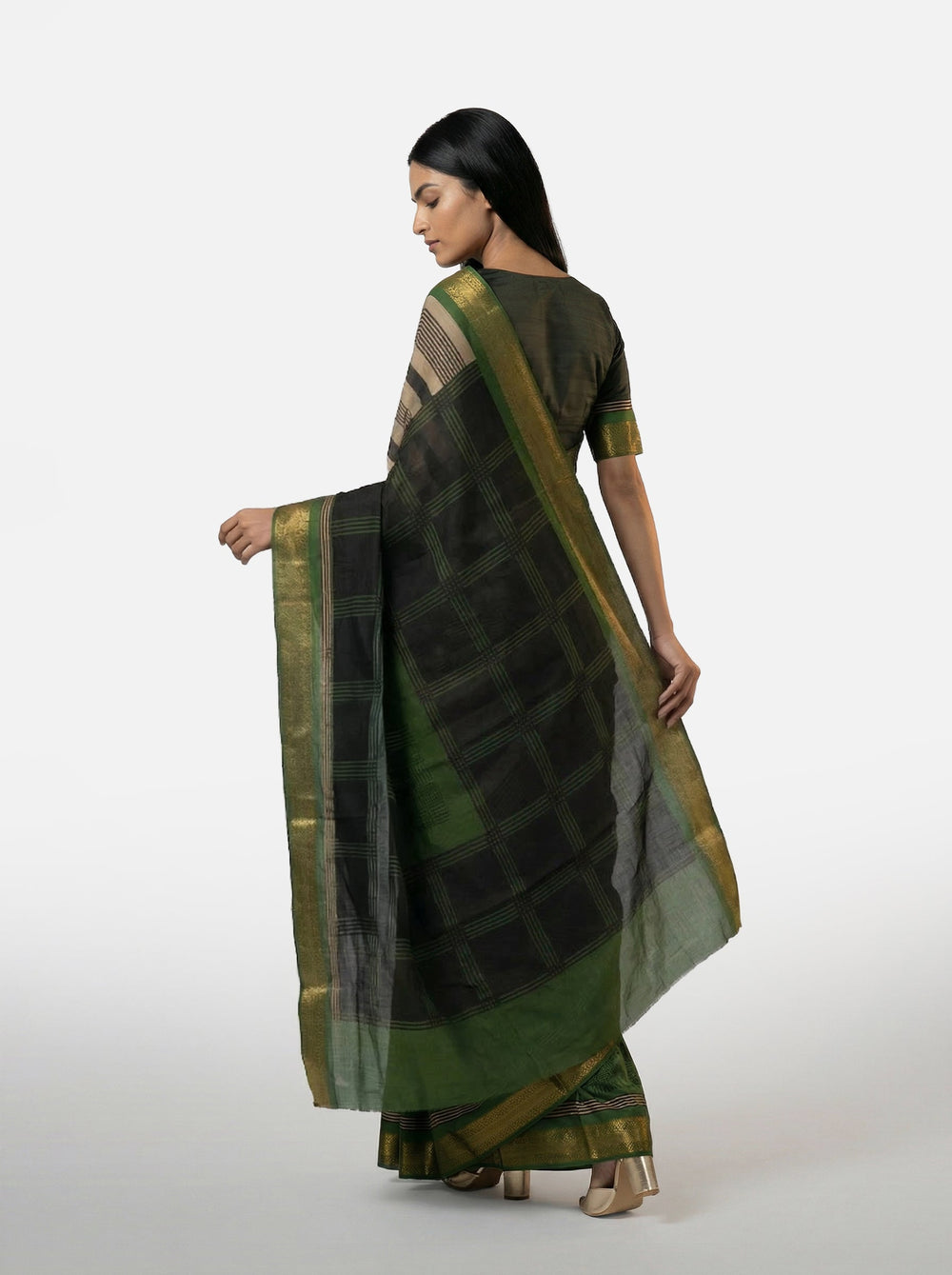 Woman wearing a traditional saree with a striped pattern against a beige wall.