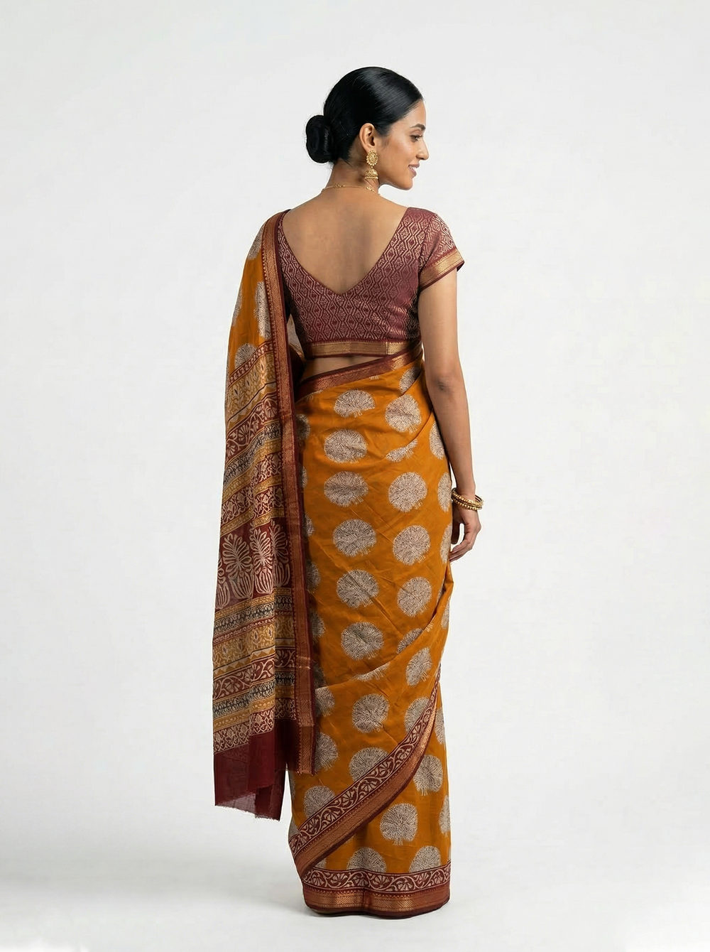 Woman wearing a traditional saree in a minimalistic setting with mirrors and decorative plants.
