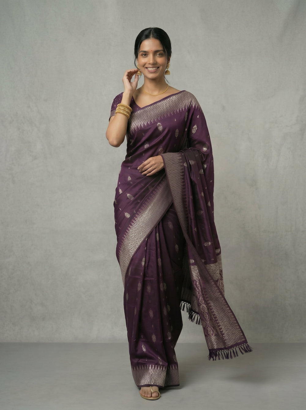 Woman wearing a purple saree with a white pattern on a gray background