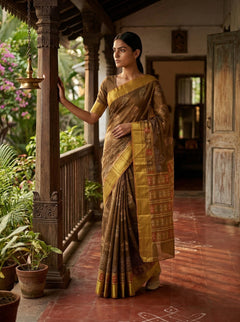 Woman in a traditional saree standing on a wooden floor with plants and architectural elements in the background