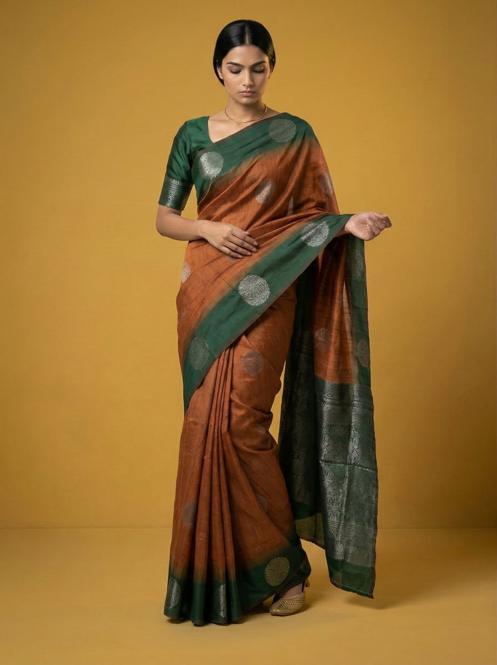 Woman wearing a brown and green saree against a yellow background