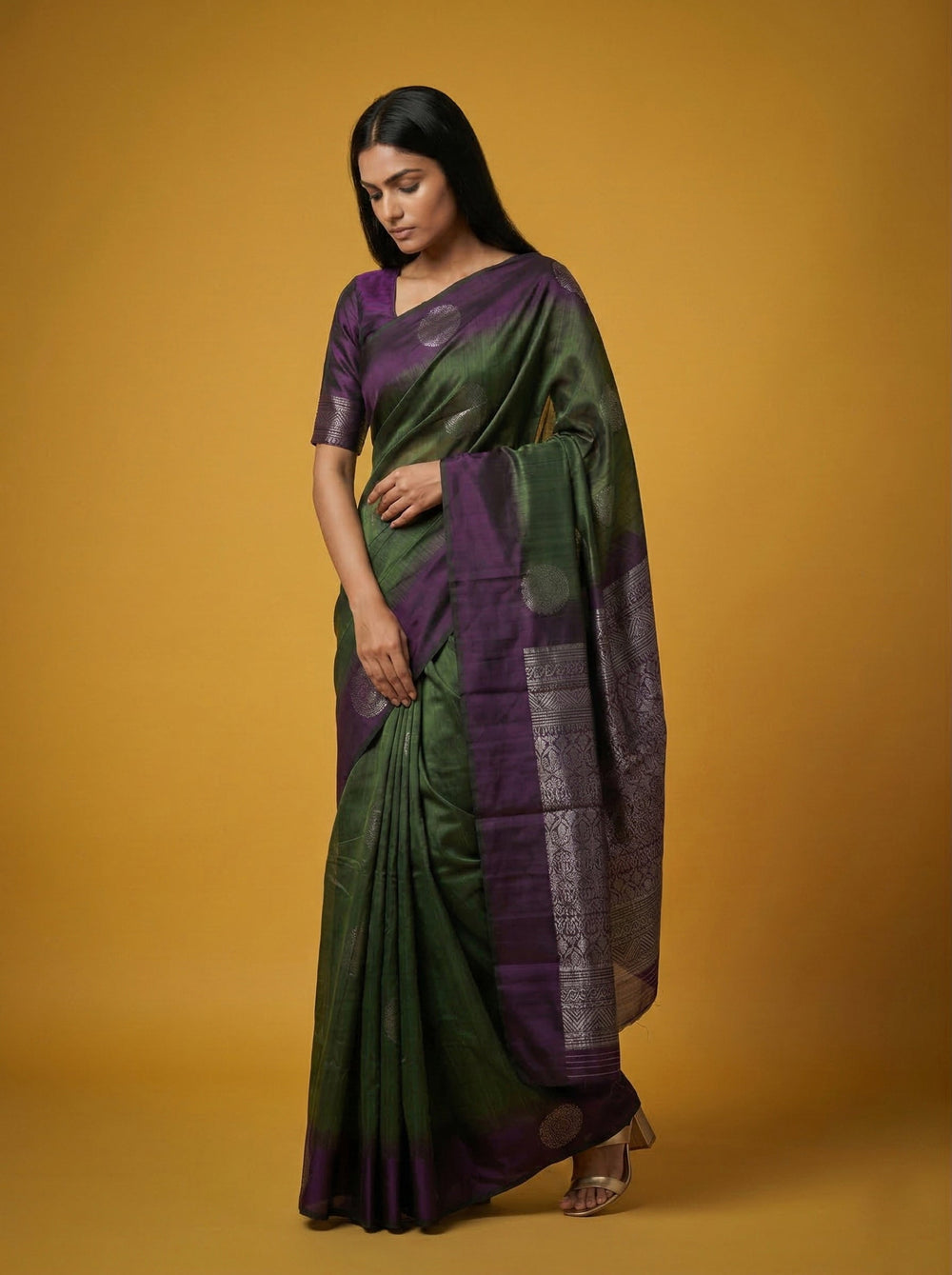 Woman wearing a green and purple saree against a yellow background