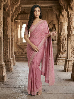 Woman in a pink saree standing in an architectural setting