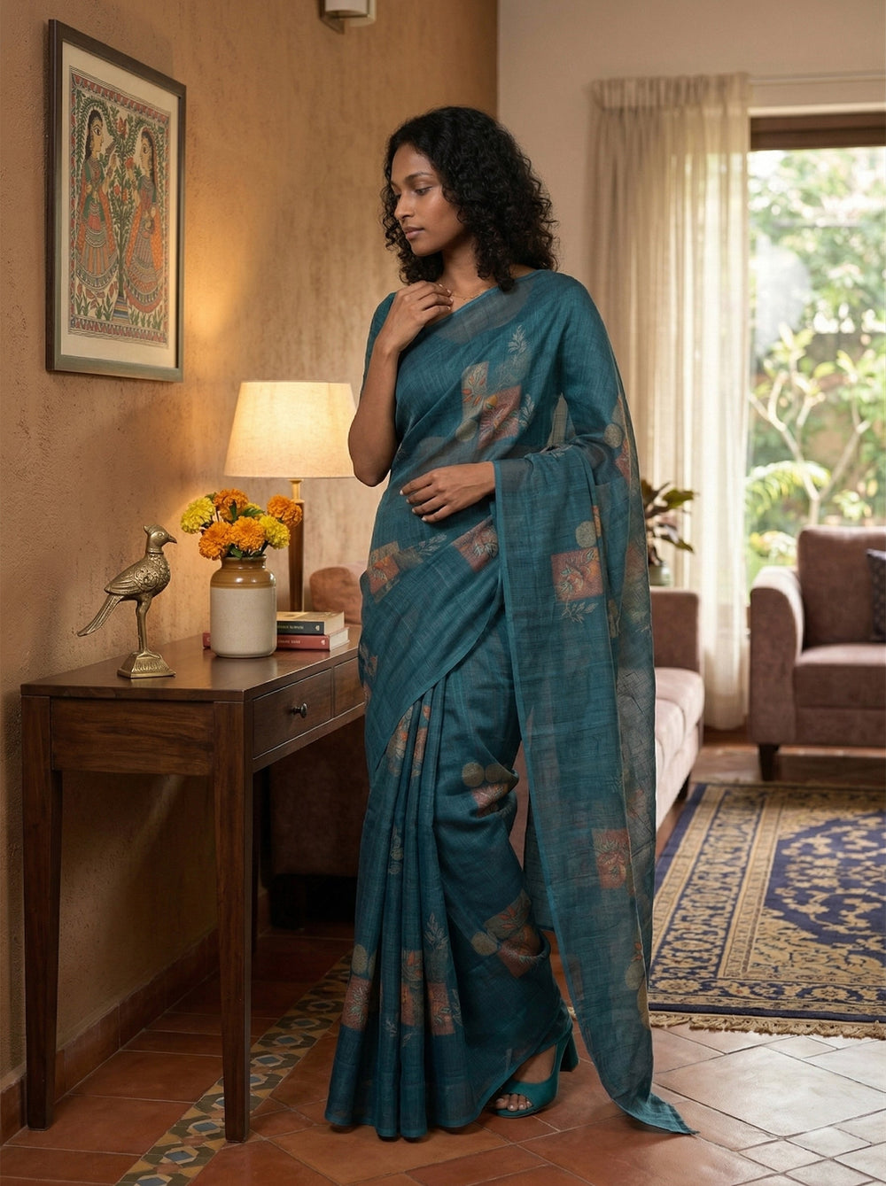 Woman in a blue saree standing in a living room with decor elements.