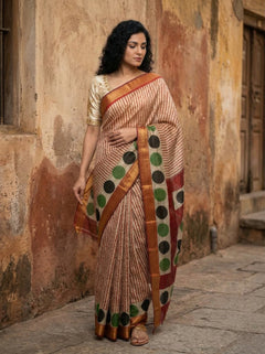 Woman wearing a traditional saree with a polka dot pattern against an old wall.