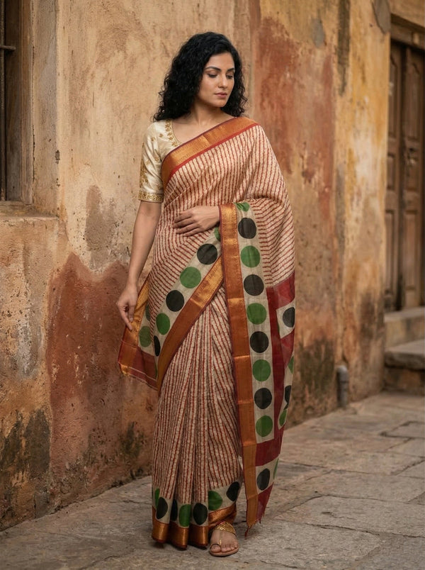 Woman wearing a traditional saree with a polka dot pattern against an old wall.