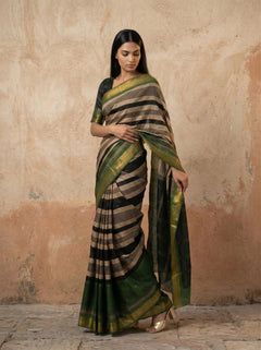 Woman wearing a traditional saree with a striped pattern against a beige wall.