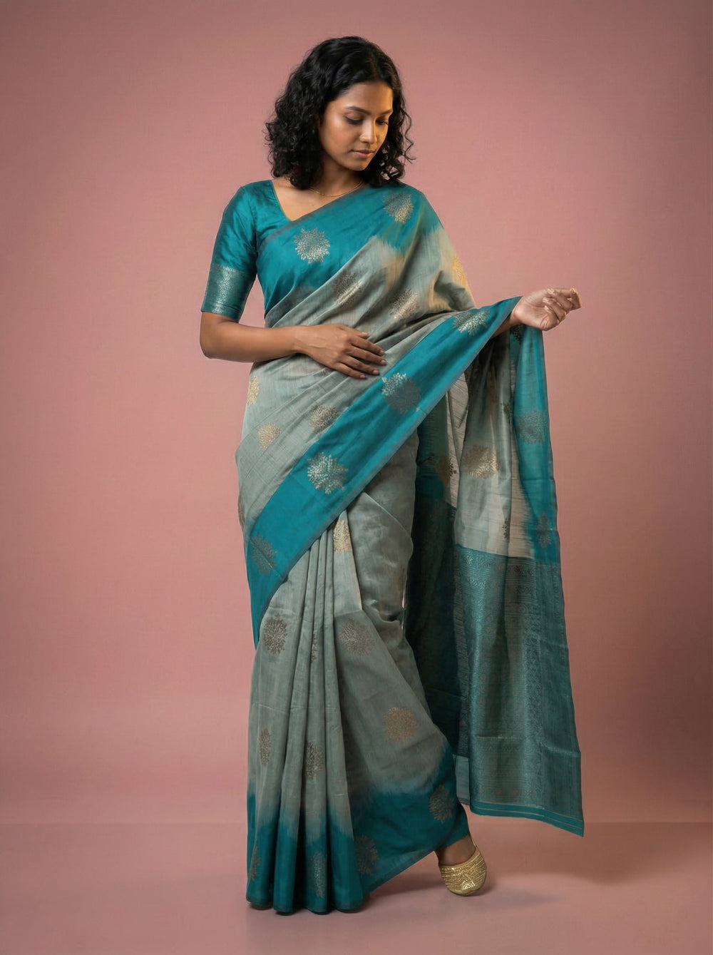 Woman wearing a teal saree with a subtle pattern on a pink background