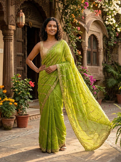 Woman in a green saree standing in front of a decorative building with flowers.