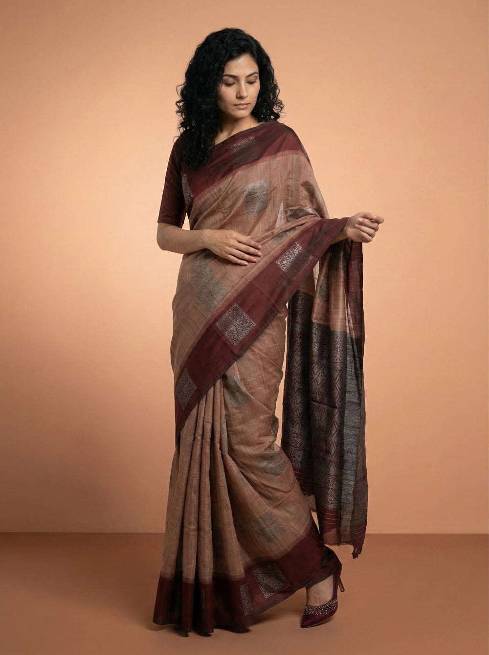 Woman wearing a traditional saree against a beige background
