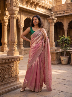 Woman in a pink saree standing in front of an architectural structure