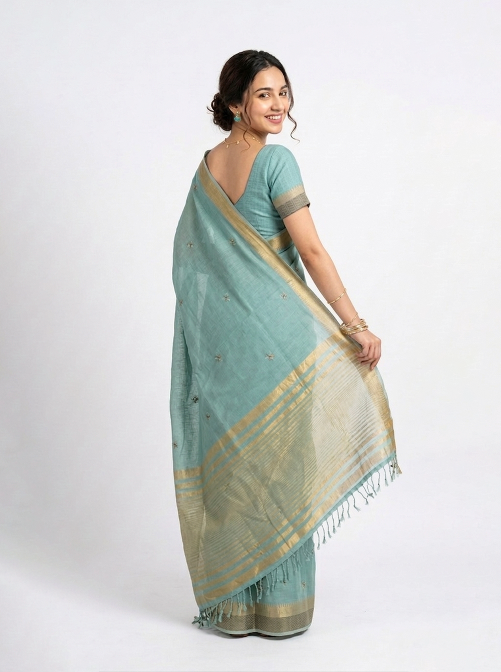 Woman in a light blue saree standing against an ornate dark wooden background