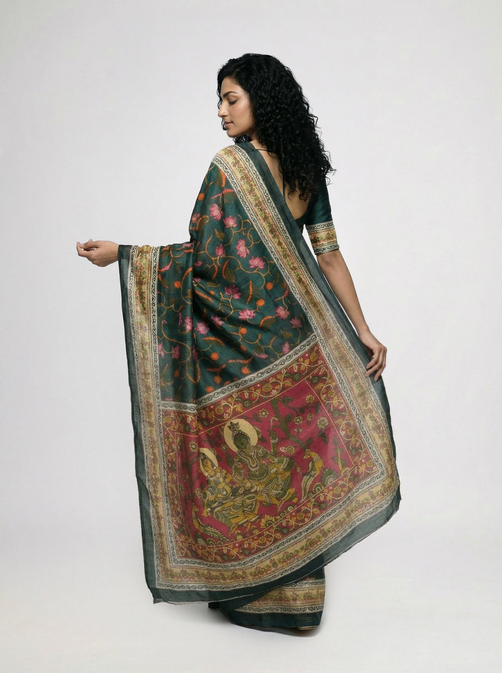 Woman in a traditional saree standing in a room with decor elements.
