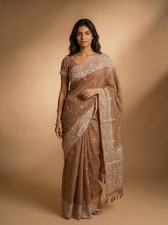 Woman wearing a brown saree with a beige background