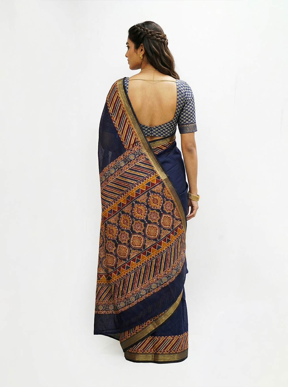 Woman wearing a navy blue saree with a patterned border, standing in front of a mirror.