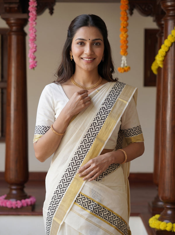 A woman wearing a traditional Indian saree with a cream body, black geometric border pattern, and gold trim, standing in a decorated indoor setting with wooden pillars and flower garlands.