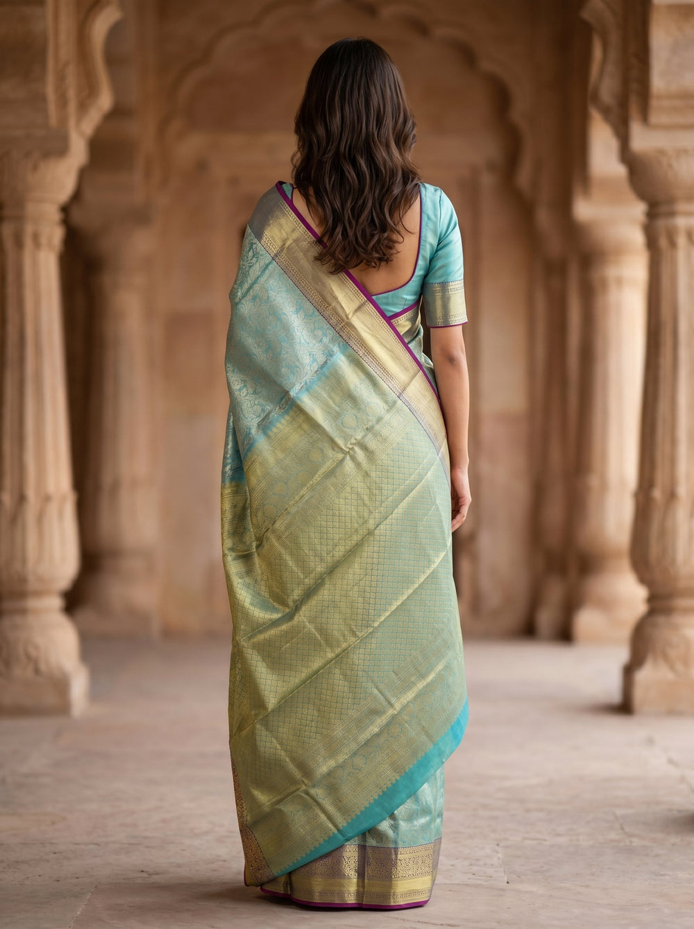 Woman in a traditional saree standing in an architectural setting