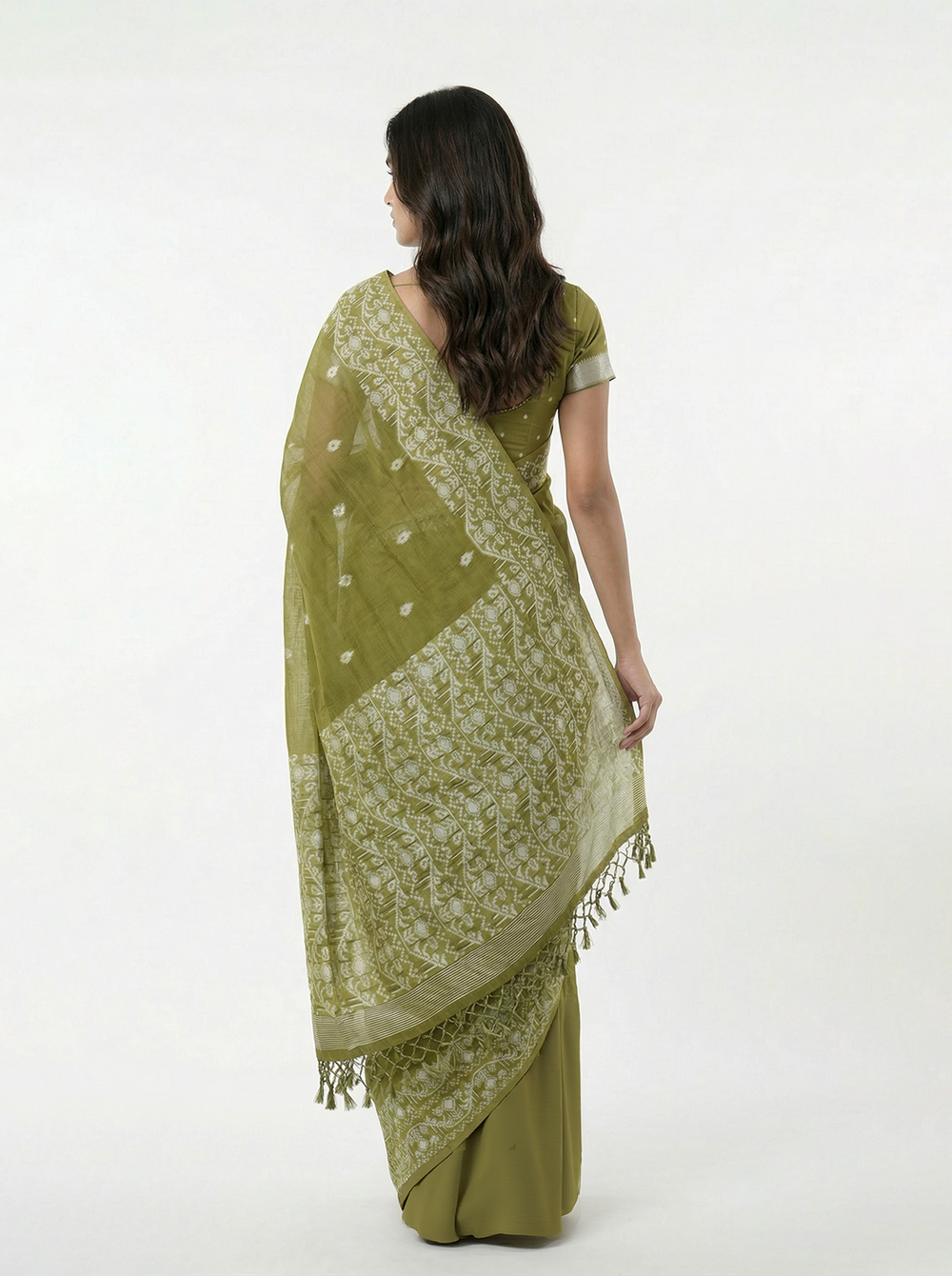 Woman wearing a green saree with a matching blouse against a teal background