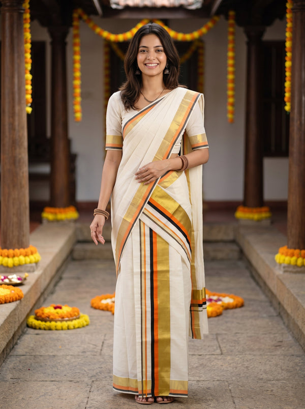A woman wearing a cream-colored cotton saree with gold, orange, and black stripes, paired with a matching cream blouse, standing in a decorated courtyard.