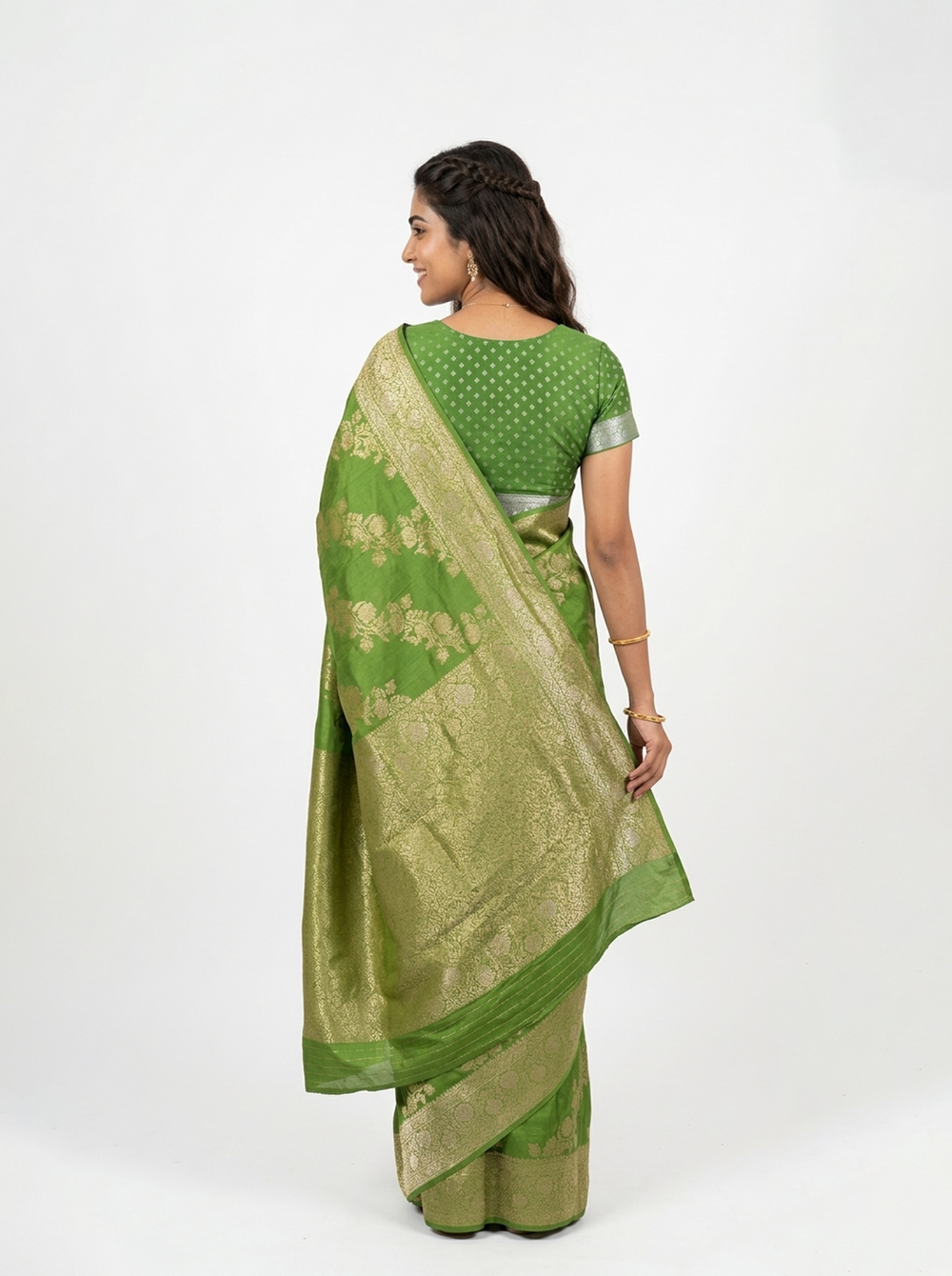 Woman in a green saree standing on a path with trees in the background