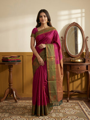 Woman in a traditional saree standing in a room with wooden furniture and a mirror.